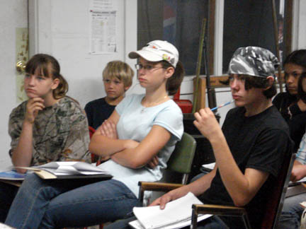 Image of teenagers sitting in chairs listening to someone talking.